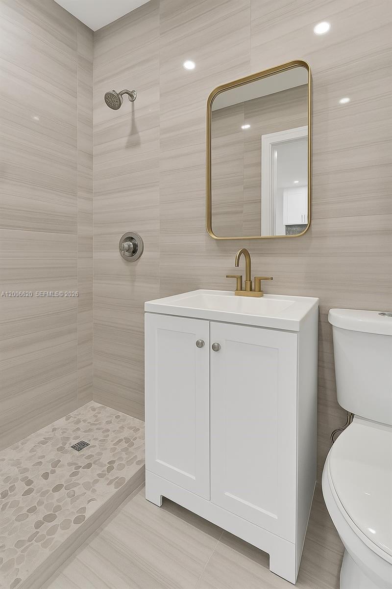 A modern bathroom features a white vanity, a gold-framed mirror, and a tiled walk-in shower — 5807 SW 25th St # 0, West Park FL 33023, WEST PARK, FL