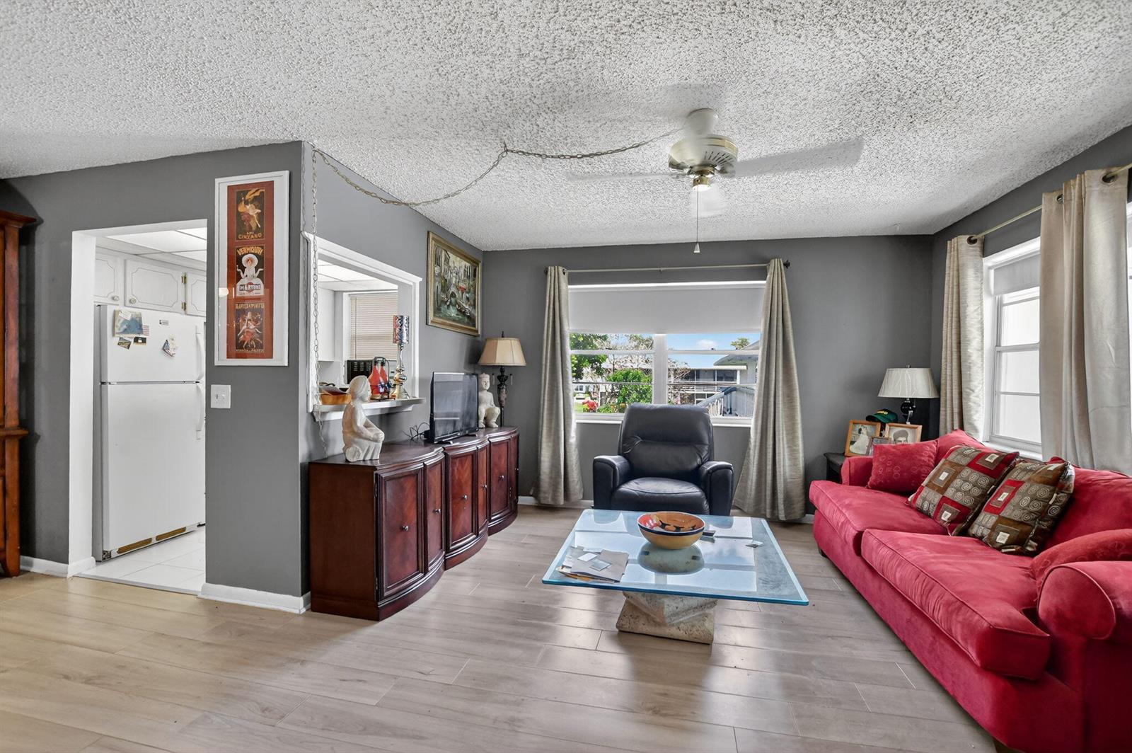 A living room features gray walls, a red sofa, a glass coffee table, and wood flooring — 313 Durham Circle # I, Deerfield Beach FL 33442, DEERFIELD BEACH, FL