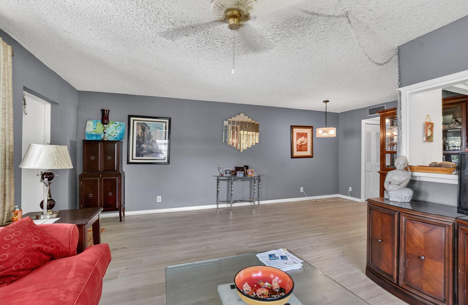 A living room with gray walls, light wood-look flooring, a ceiling fan, and traditional furniture — 313 Durham Circle # I, Deerfield Beach FL 33442, DEERFIELD BEACH, FL