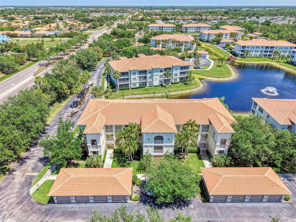 An aerial view shows a multi-story apartment building with a tile roof and detached garages — 900 SAN LINO CIRCLE UNIT # 910, VENICE, FL