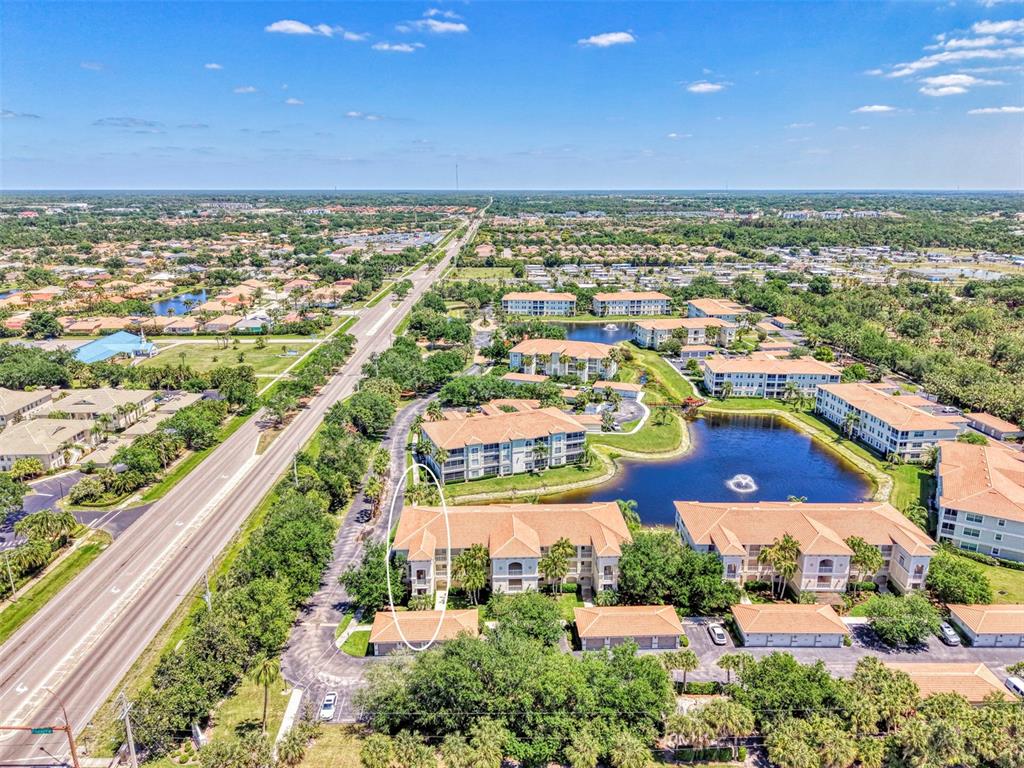 An aerial view shows a multi-story apartment complex with a lake and surrounding neighborhood — 900 SAN LINO CIRCLE UNIT # 910, VENICE, FL