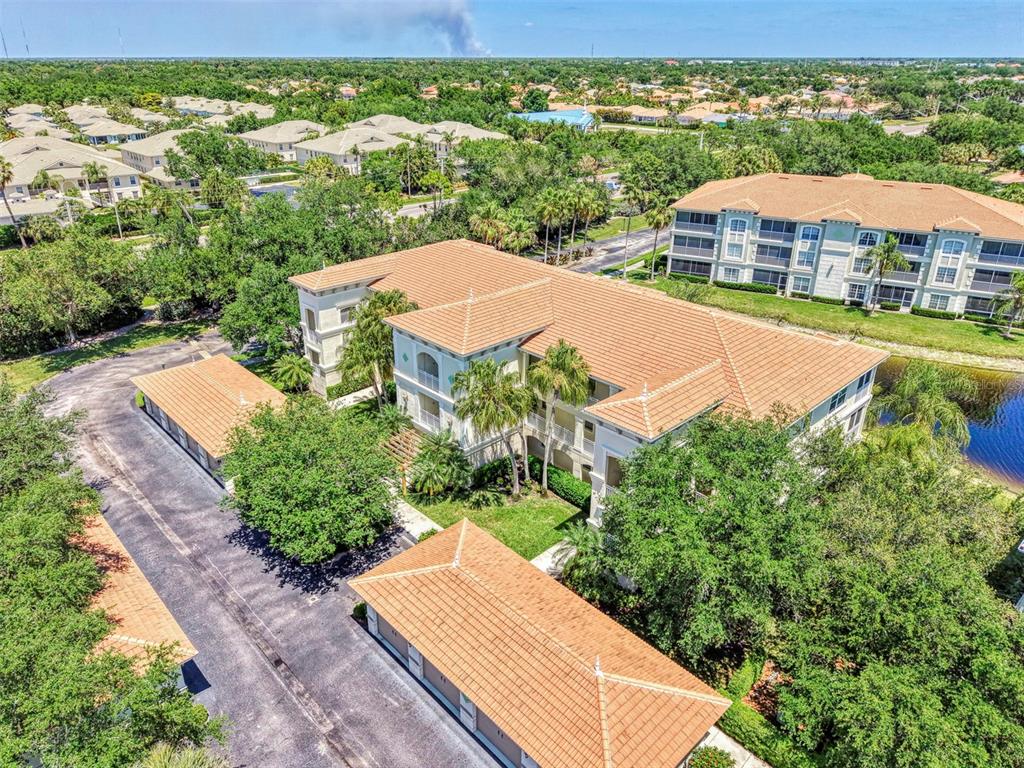 An aerial view shows a multi-story apartment building with a tiled roof and detached garages — 900 SAN LINO CIRCLE UNIT # 910, VENICE, FL