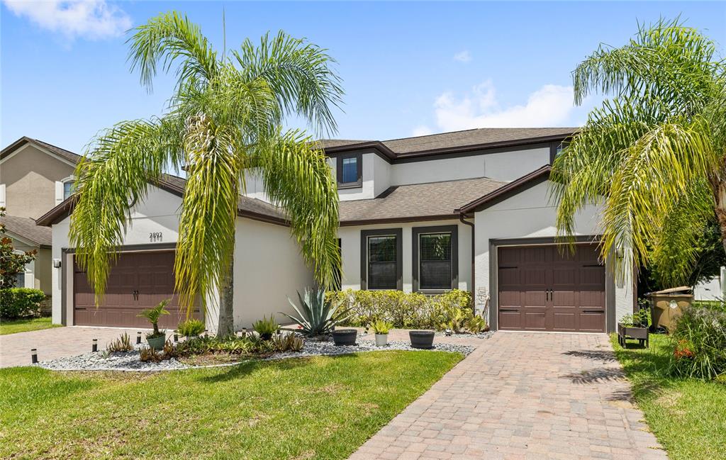 A two-story house with a paved driveway, two garage doors, and palm trees in front — 2892 SPRING BREEZE WAY, KISSIMMEE, FL