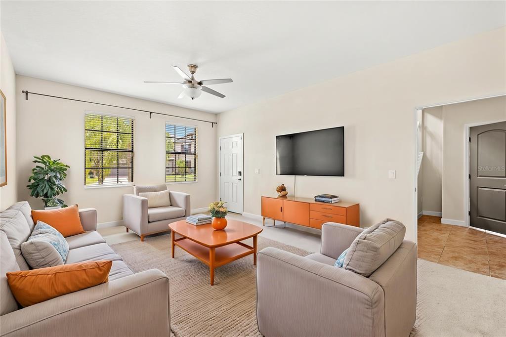 A living room features a sofa, two armchairs, a coffee table, and a wall-mounted television — 2892 SPRING BREEZE WAY, KISSIMMEE, FL