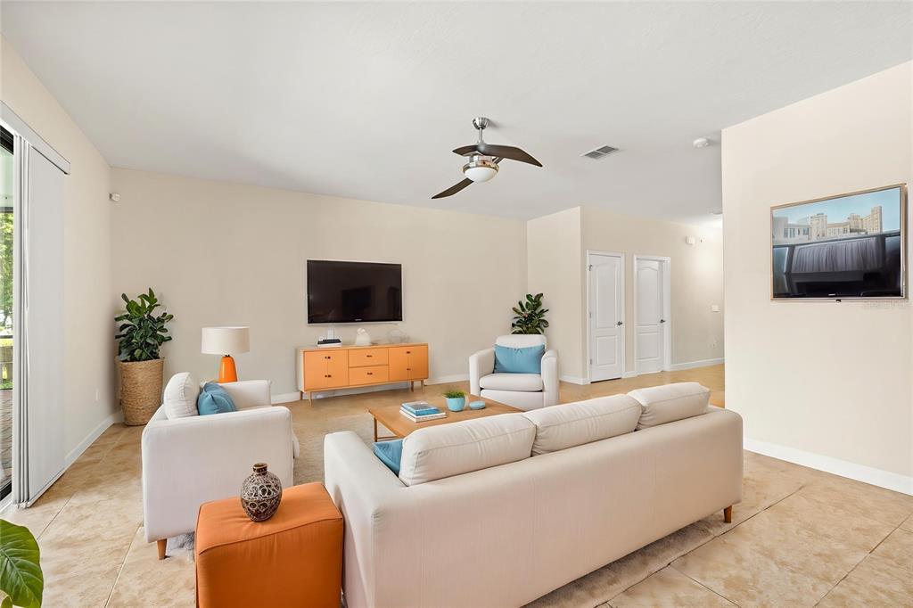 A living room features a beige sofa, two armchairs, an orange console, and tile flooring — 2892 SPRING BREEZE WAY, KISSIMMEE, FL