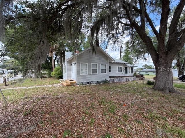 A light gray, single-story house with a gabled roof sits under large, moss-covered oak trees — 373 E WALDO STREET, GROVELAND, FL