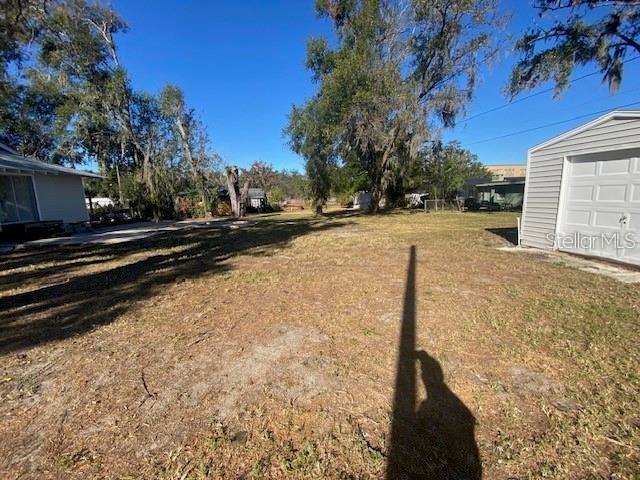 A grassy backyard sits between a house on the left and a garage on the right — 373 E WALDO STREET, GROVELAND, FL