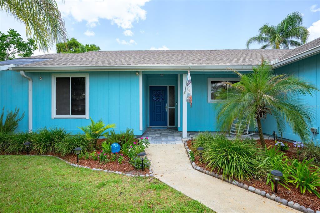 The exterior of a blue single-story house features a front walkway and landscaping — 1123 SHERBOURNE WAY, ORMOND BEACH, FL