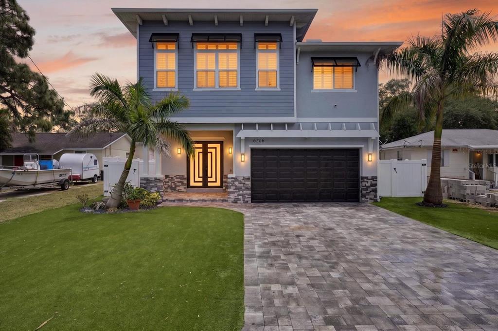 A two-story house with blue siding, a dark garage door, and a paved driveway — 6706 S STERLING AVENUE, TAMPA, FL