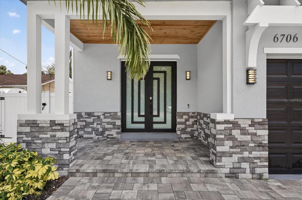 A modern front entrance features a double door, stone veneer siding, and a wood-paneled ceiling — 6706 S STERLING AVENUE, TAMPA, FL