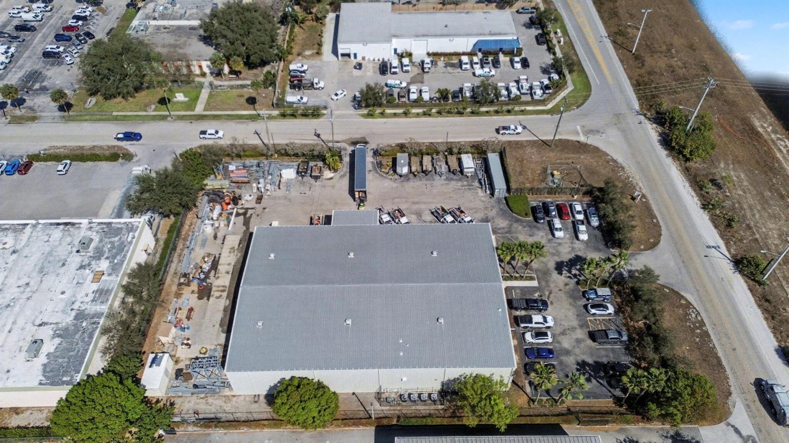 An aerial view shows a commercial building with a large parking lot and storage yard — 6861 Garden Road, Riviera Beach FL 33404, RIVIERA BEACH, FL