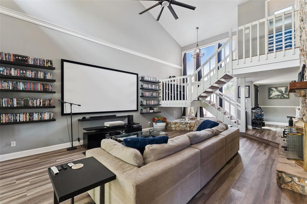 A living room features a stone fireplace, a staircase with white railings, and wood flooring — 1200 ROYAL OAK DRIVE, WINTER SPRINGS, FL
