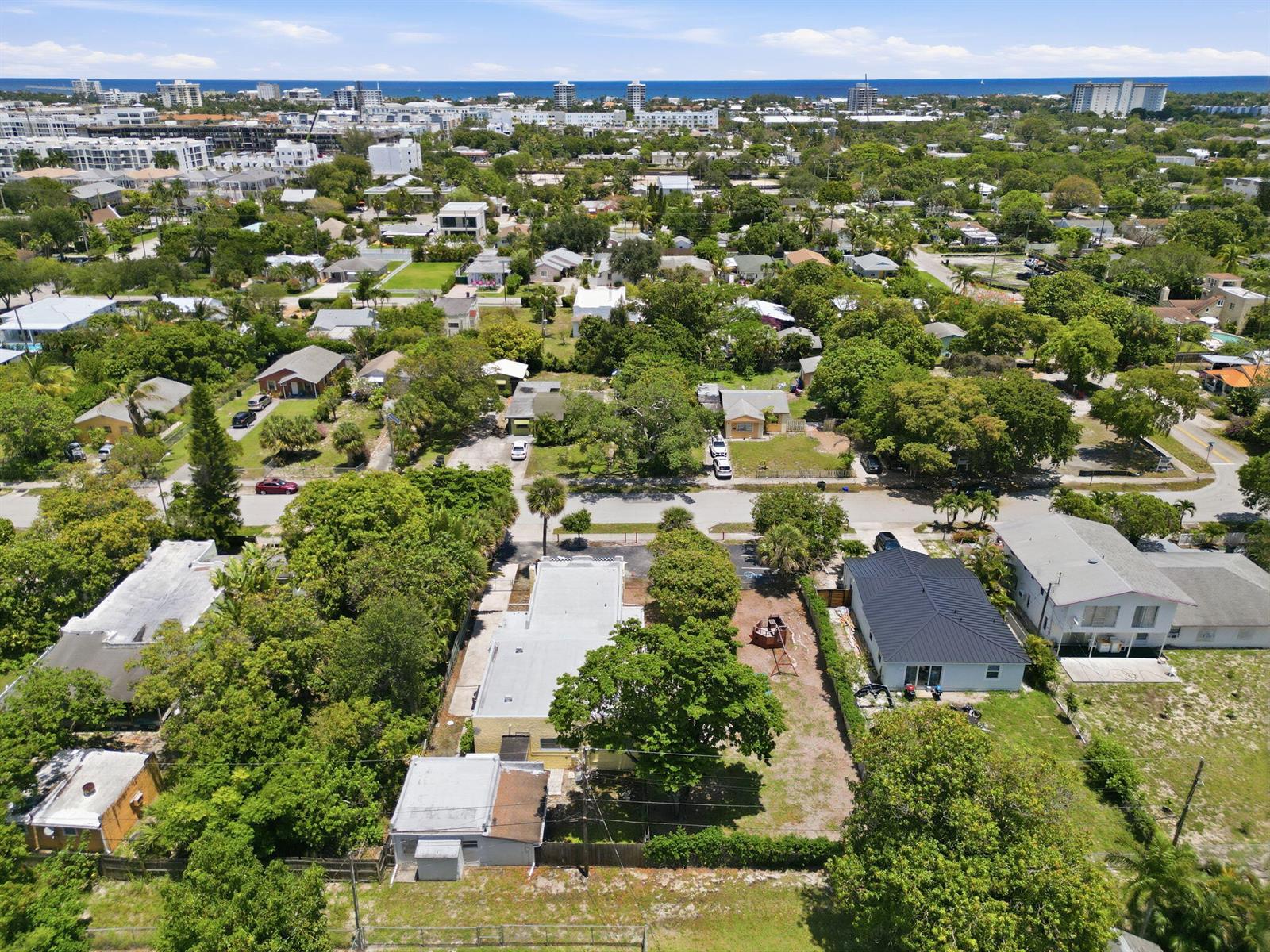 An aerial view shows a residential neighborhood with houses, trees, and a distant ocean horizon — 216 SW 2nd Avenue, Delray Beach FL 33444, DELRAY BEACH, FL