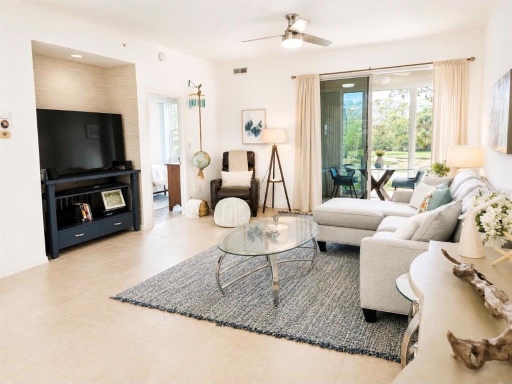 A living room features a sectional sofa, glass coffee table, television console, and sliding glass doors — 8360 WINGATE DRIVE UNIT 811, SARASOTA, FL