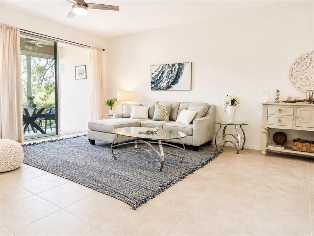 A living room features a sectional sofa, glass coffee table, area rug, and sliding glass doors — 8360 WINGATE DRIVE UNIT 811, SARASOTA, FL