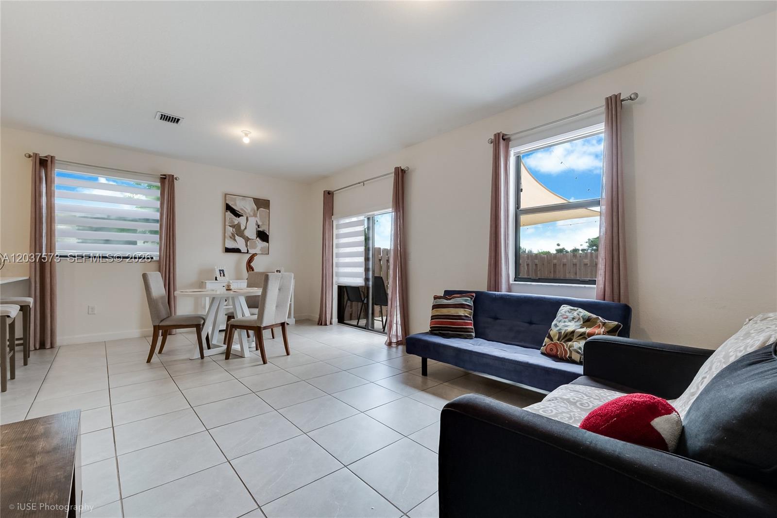 A living and dining area with tile flooring, a blue sofa, and a glass sliding door — 23105 SW 128th Pl # 23105, Miami FL 33170, MIAMI, FL