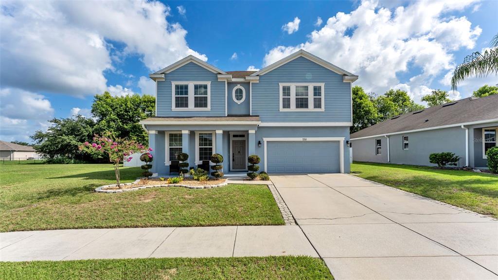 A two-story blue house with a two-car garage and a front lawn — 1358 WINDWARD OAKS LOOP, AUBURNDALE, FL