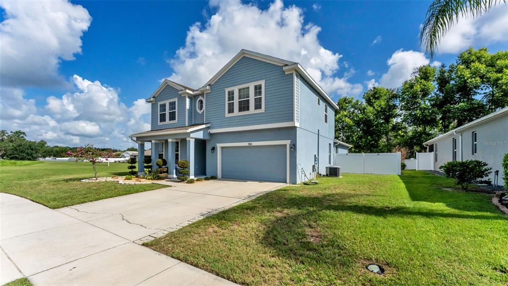 A two-story blue house with a two-car garage and a white vinyl fence — 1358 WINDWARD OAKS LOOP, AUBURNDALE, FL