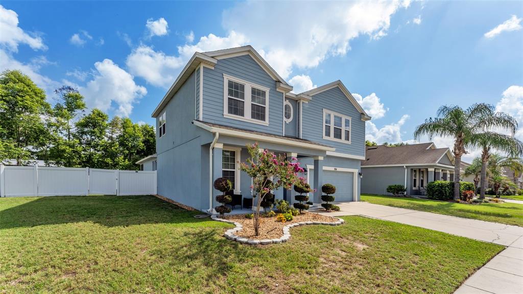 A two-story blue house features a front porch, a garage, and a landscaped yard — 1358 WINDWARD OAKS LOOP, AUBURNDALE, FL