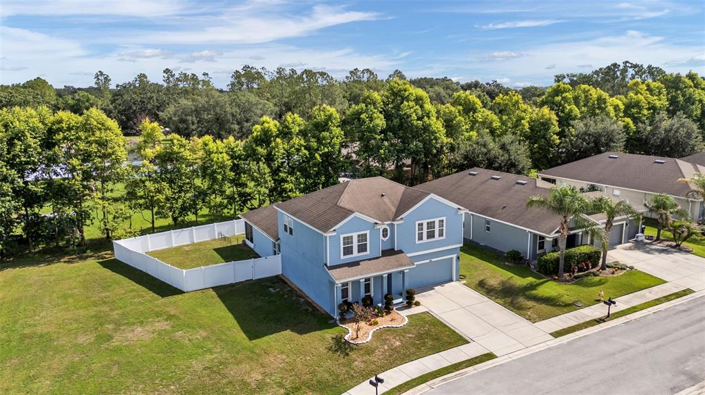 An aerial view of a two-story blue house with a white fence and driveway — 1358 WINDWARD OAKS LOOP, AUBURNDALE, FL