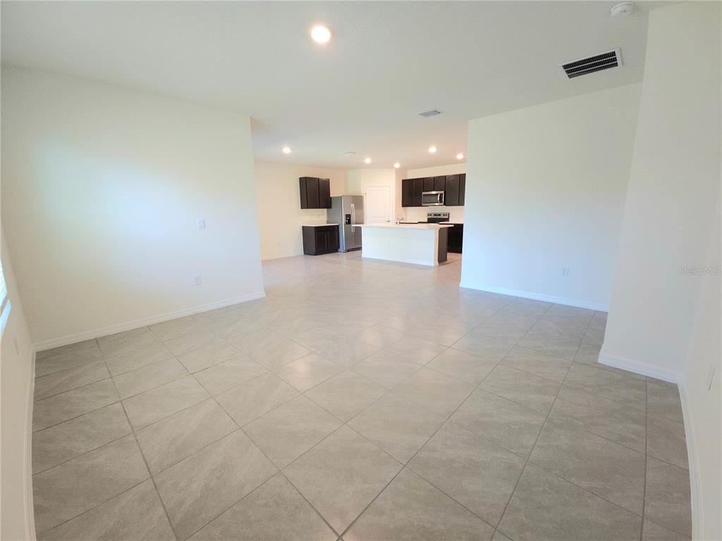 An open-concept living area features light-colored tile flooring and a kitchen with dark cabinetry — 296 HICKORY COURSE TRAIL, OCALA, FL