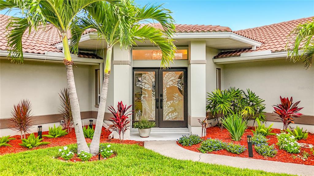 The exterior entrance of a house features a double door with etched glass palm designs — 324 LEEWARD ISLAND, CLEARWATER BEACH, FL