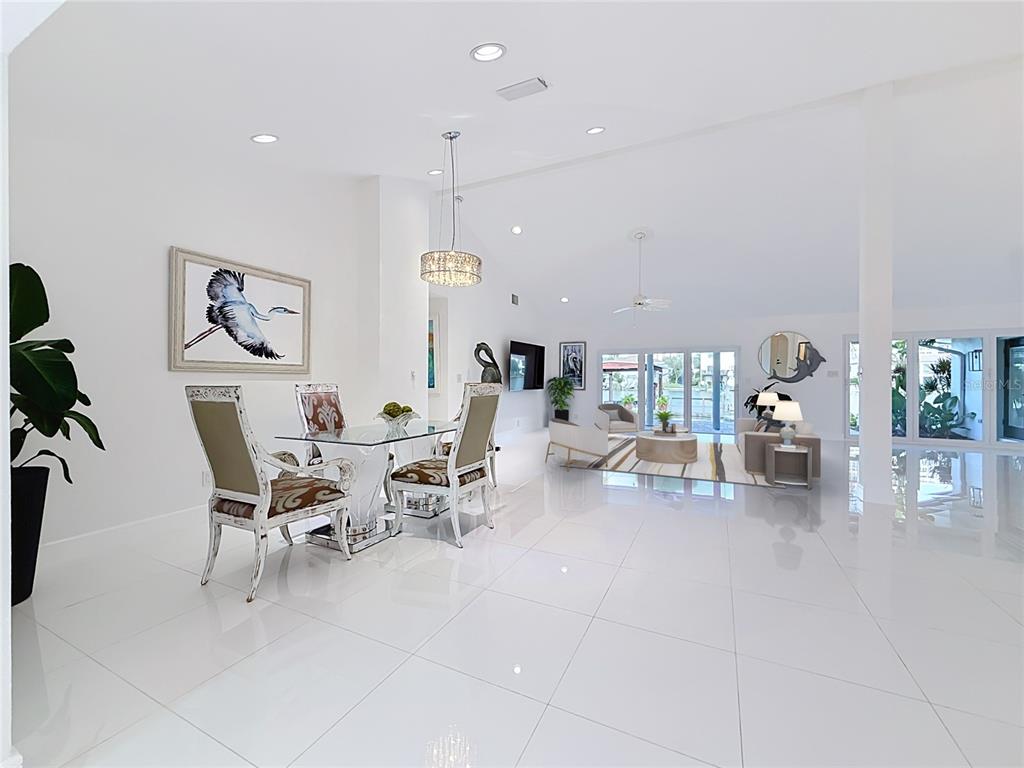 A bright, open-concept dining and living area features white tile floors and large glass doors — 324 LEEWARD ISLAND, CLEARWATER BEACH, FL