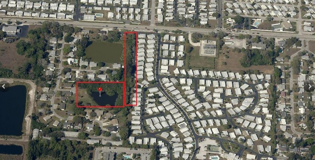 An aerial view shows a rectangular plot of land containing a pond and wooded area — ALGERIA COURT, BRADENTON, FL