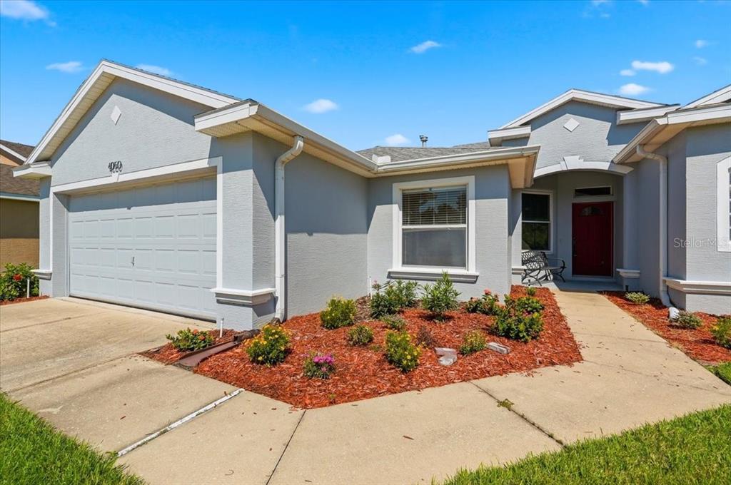A single-story house with a gray exterior, a two-car garage, and a red front door — 4050 WHISTLEWOOD CIRCLE, LAKELAND, FL