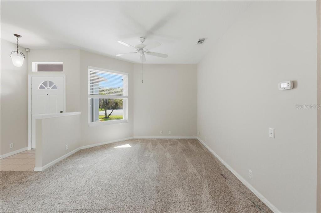 An empty room with beige carpet, light-colored walls, a ceiling fan, and a front door — 4050 WHISTLEWOOD CIRCLE, LAKELAND, FL