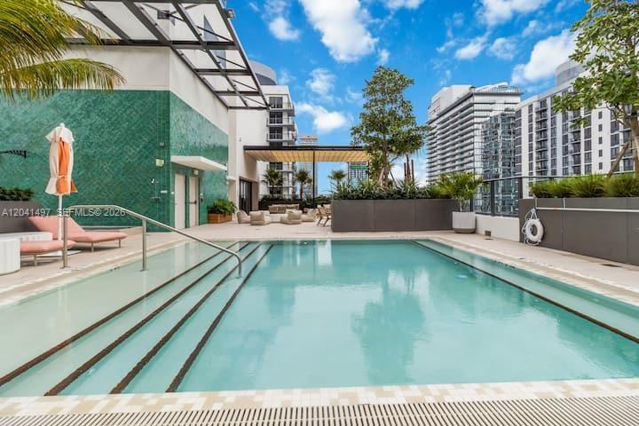 A swimming pool with steps and lounge chairs on a modern building's rooftop terrace — 11 NE 6th St # 807, Miami FL 33132, MIAMI, FL