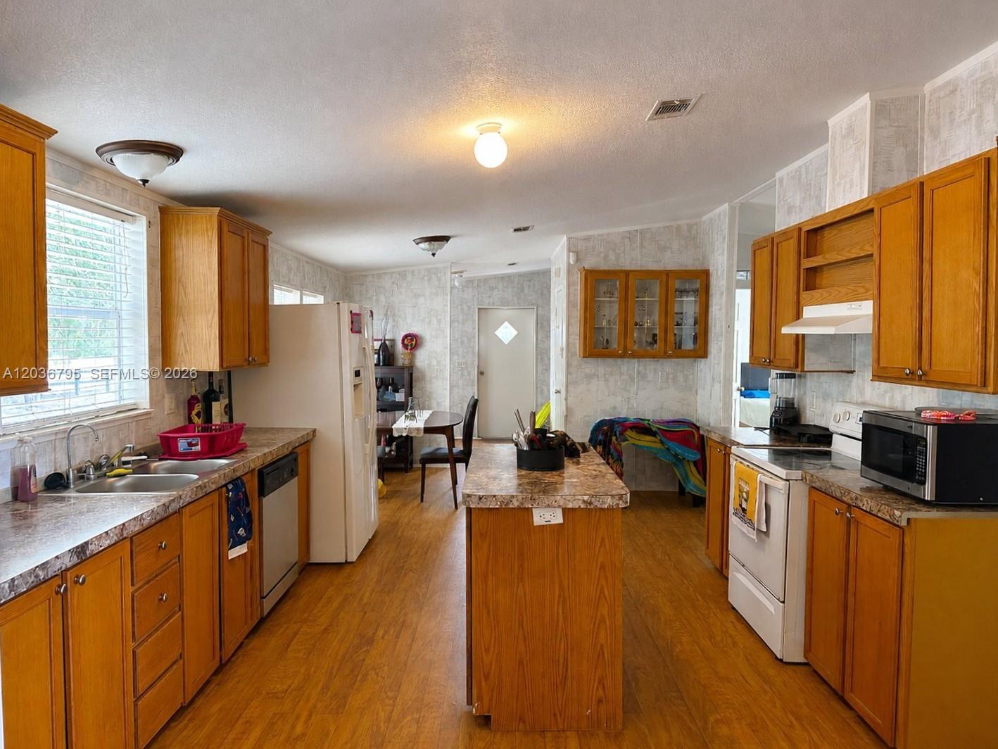 A kitchen features wood cabinets, laminate countertops, a center island, and white appliances — 1 Ridge Rd, Frostproof FL 33843, FROSTPROOF, FL