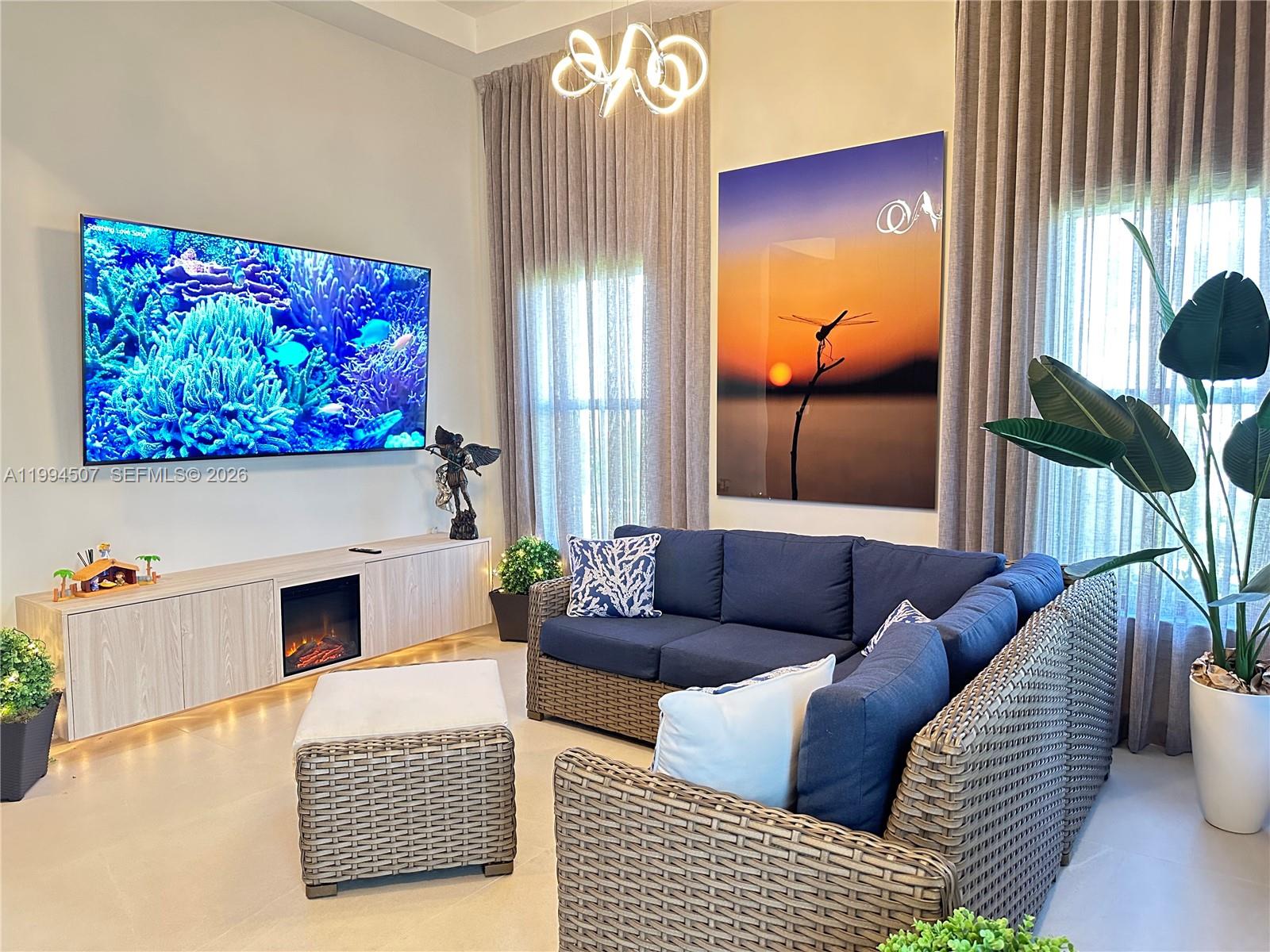 A living room features a large television, a fireplace console, and a wicker sectional sofa — 4896 Corrado Ave, Ave Maria FL 34142, AVE MARIA, FL