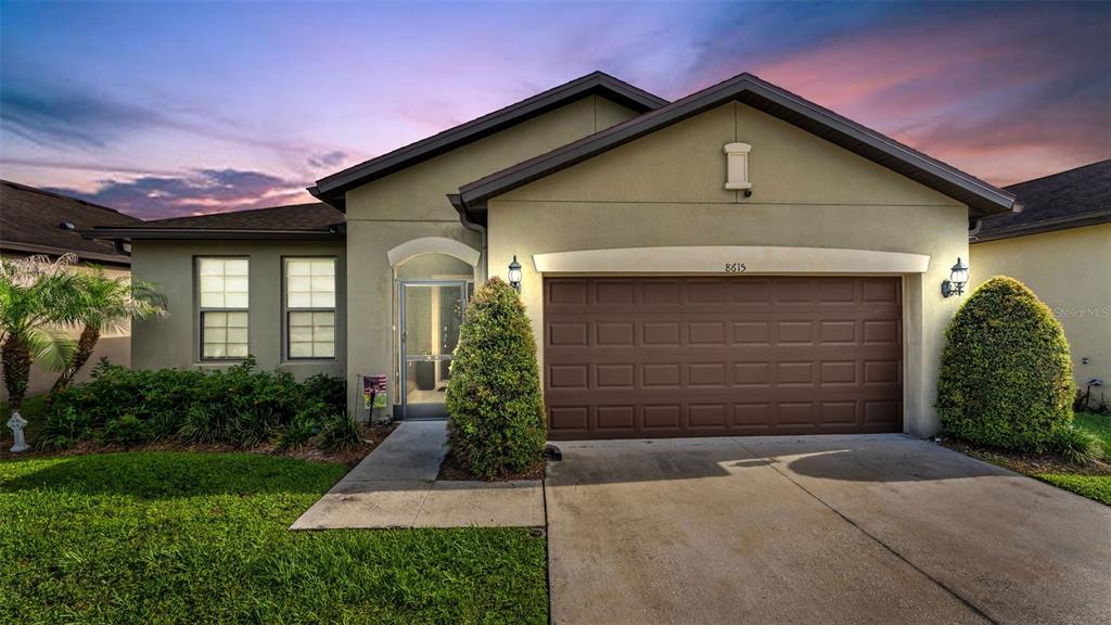 A single-story house with a brown garage door, light-colored stucco exterior, and a front lawn — 8615 RINDGE ROAD, POLK CITY, FL