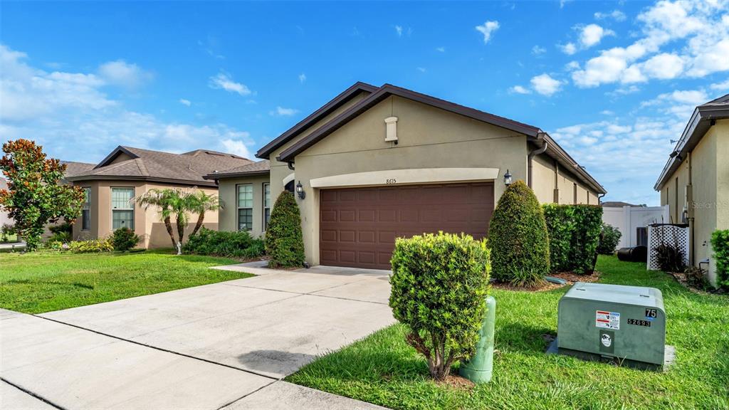 A tan single-story house with a brown garage door and a green utility box outside — 8615 RINDGE ROAD, POLK CITY, FL
