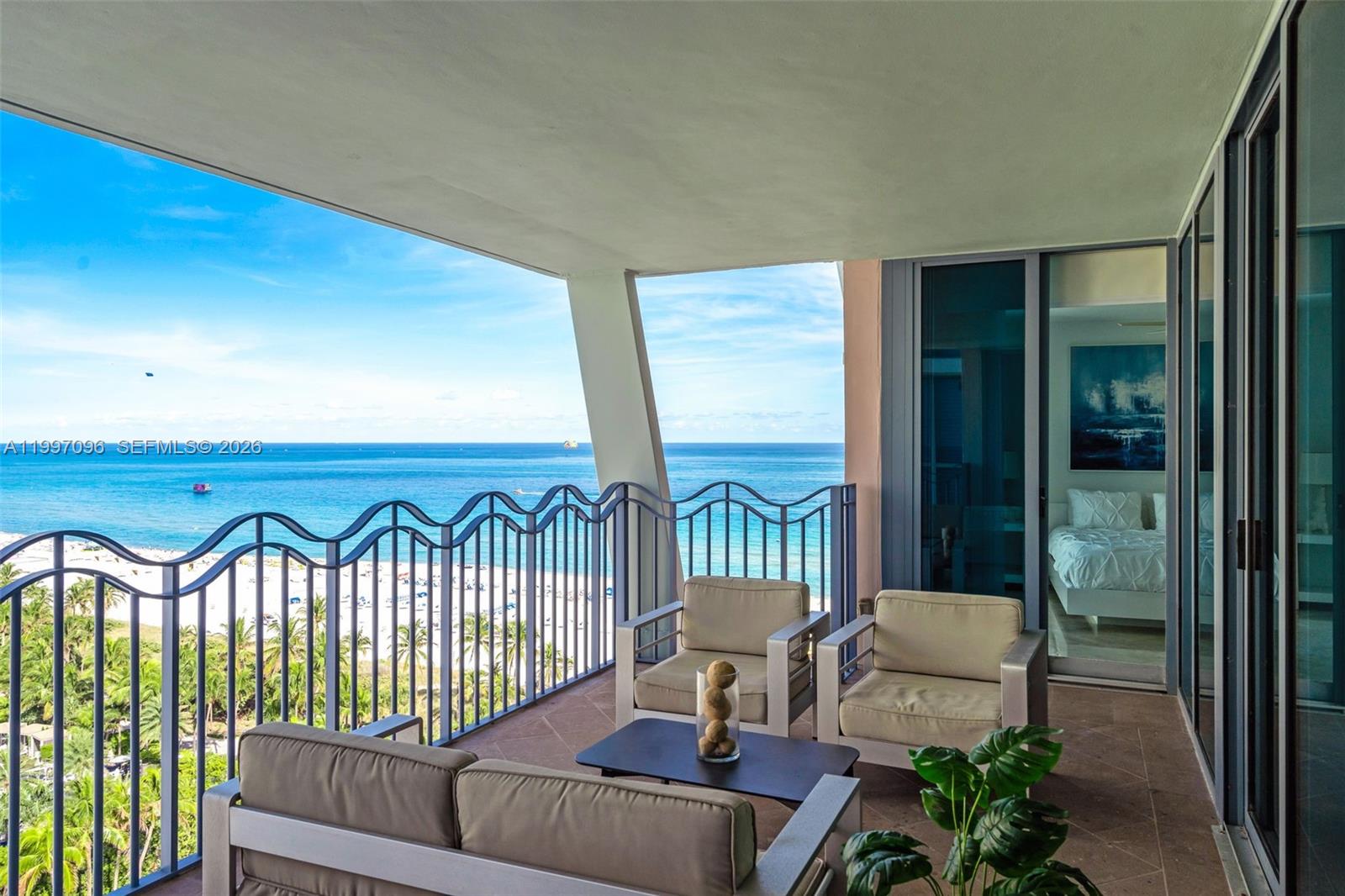 A balcony with outdoor seating overlooks a sandy beach and the ocean — 1500 Ocean Dr # 05, Miami Beach FL 33139, MIAMI BEACH, FL