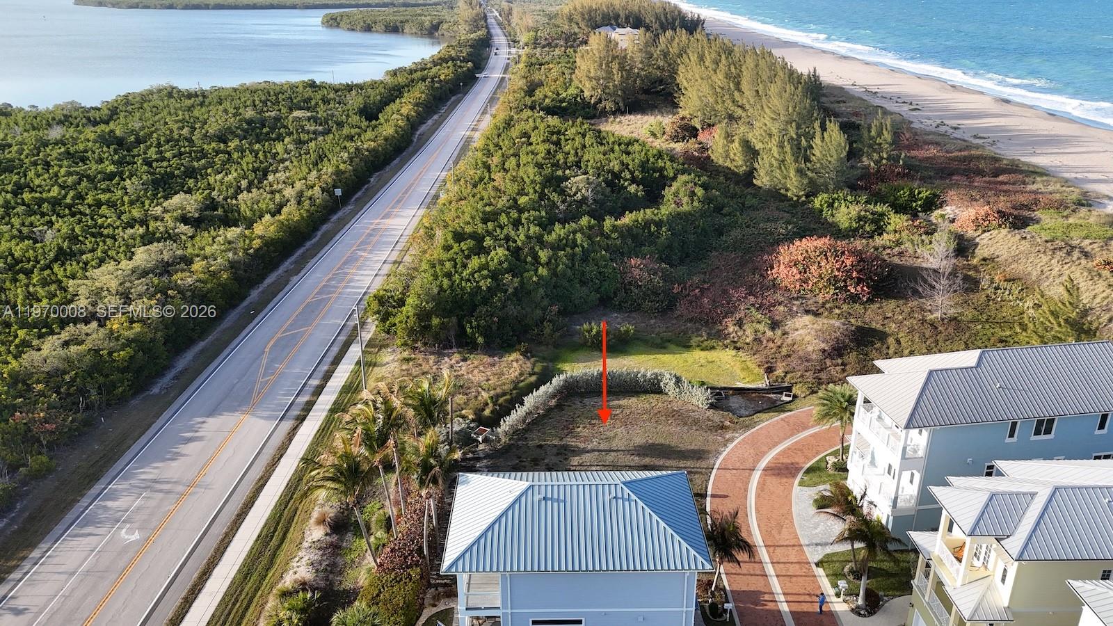 An aerial view shows a vacant residential lot situated between a road and the ocean — 4801 Watersong Way, Fort Pierce FL 34949, FORT PIERCE, FL
