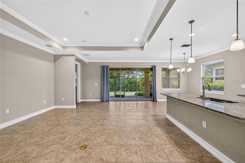 An open-concept living area with tile floors, a tray ceiling, and a kitchen island — 120 VENTOSA PLACE, NOKOMIS, FL