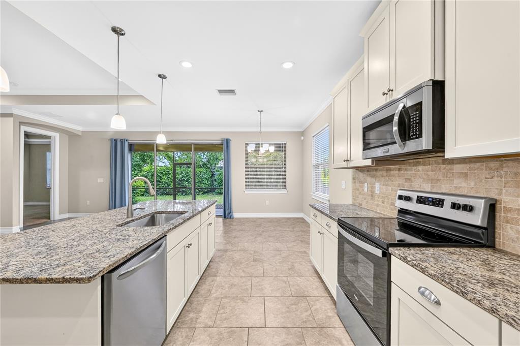 A kitchen with white cabinets, granite countertops, stainless steel appliances, and tile flooring — 120 VENTOSA PLACE, NOKOMIS, FL