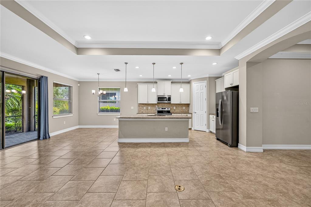 A kitchen with white cabinets, granite countertops, and tile flooring opens to a living area — 120 VENTOSA PLACE, NOKOMIS, FL