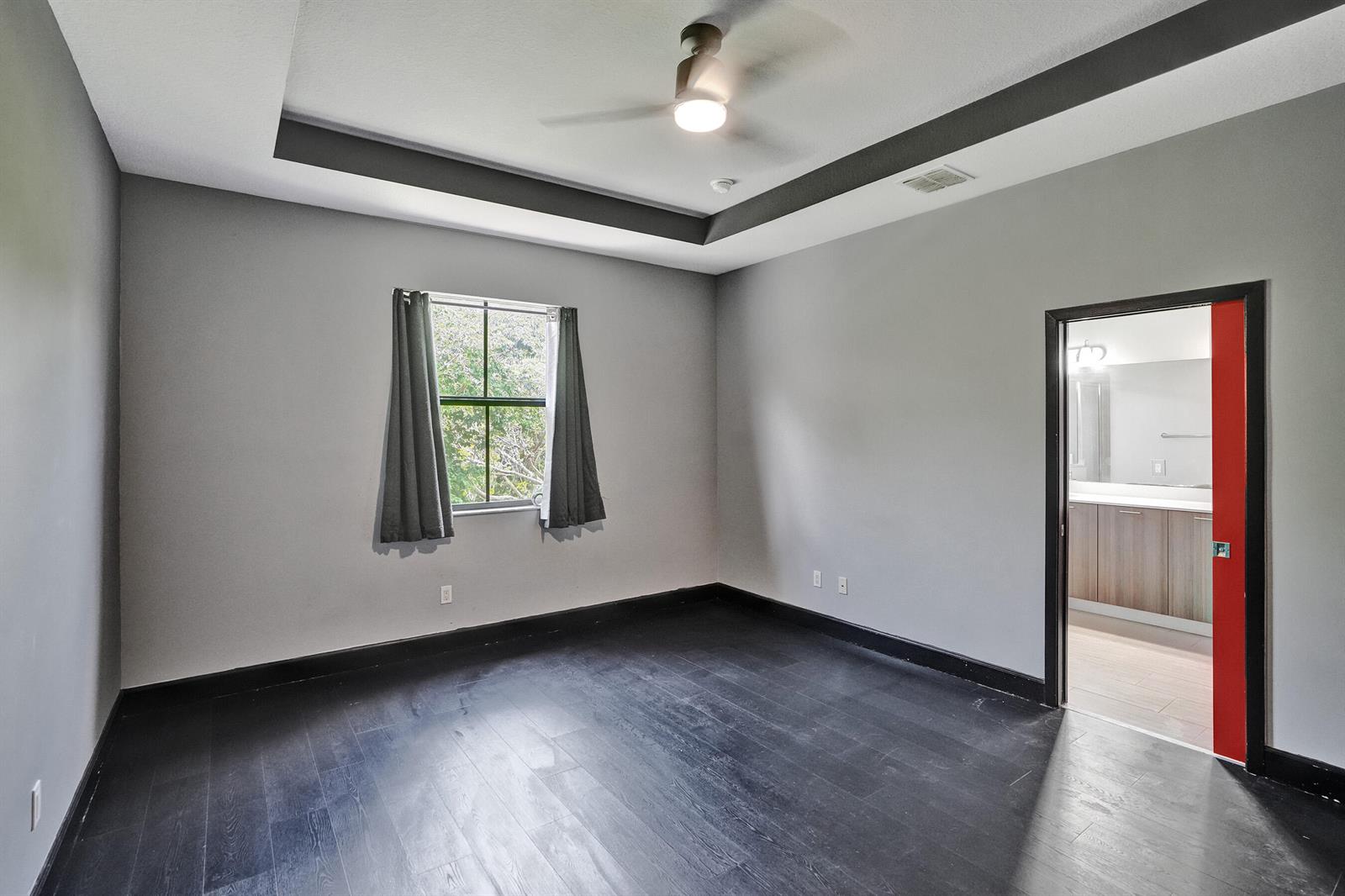 A bedroom with gray walls, dark wood flooring, a tray ceiling, and a red door — 5902 NW 46th Lane, Tamarac FL 33319, TAMARAC, FL