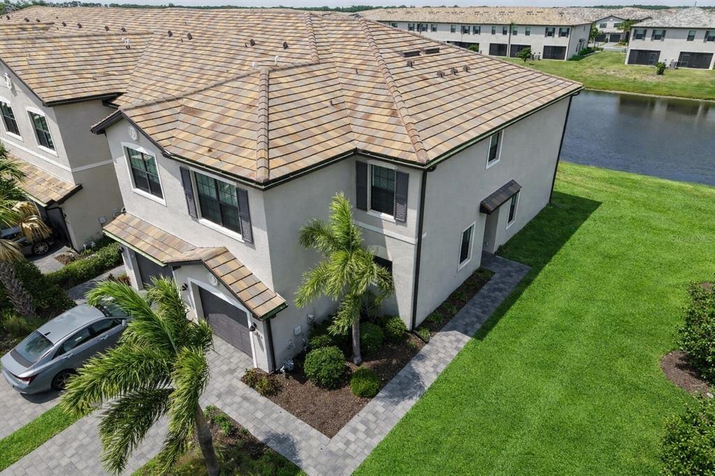 An aerial view shows a two-story townhouse with a tiled roof, garage, and side yard — 15245 LYLA TERRACE, LAKEWOOD RANCH, FL