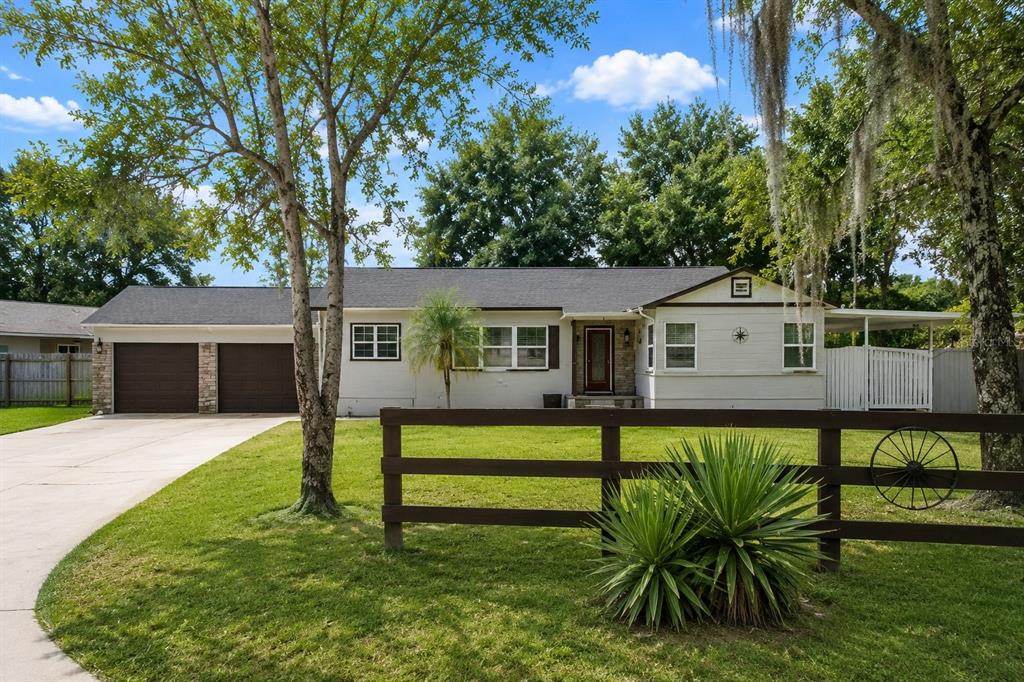 A single-story house with a two-car garage, white siding, and a wooden fence in front — 2400 S LAUREL AVENUE, SANFORD, FL