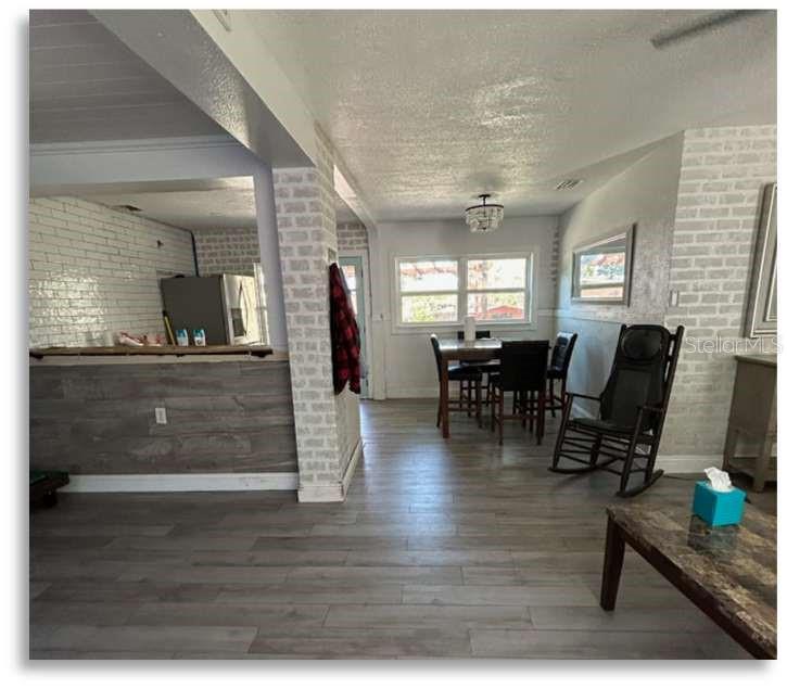 A dining area with a wooden table, chairs, and a rocking chair on wood-look flooring — 2400 S LAUREL AVENUE, SANFORD, FL