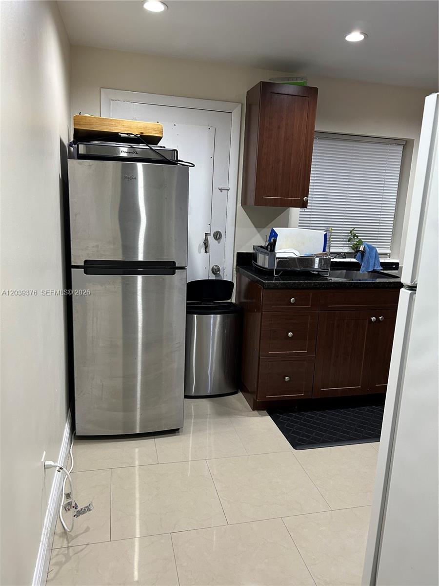 A kitchen features stainless steel appliances, dark wood cabinets, and light-colored tile flooring — NORTH MIAMI, FL