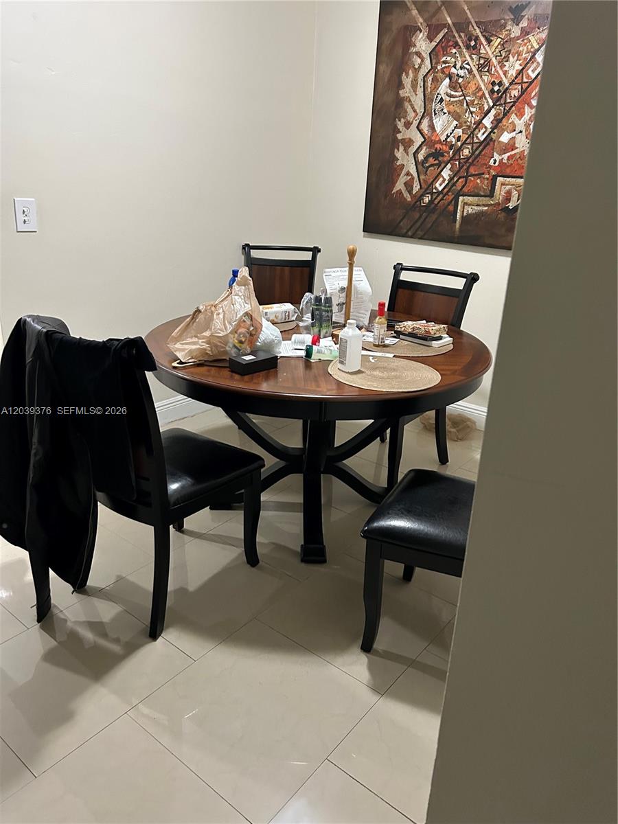 A dining area features a round wooden table with four black chairs and wall art — NORTH MIAMI, FL