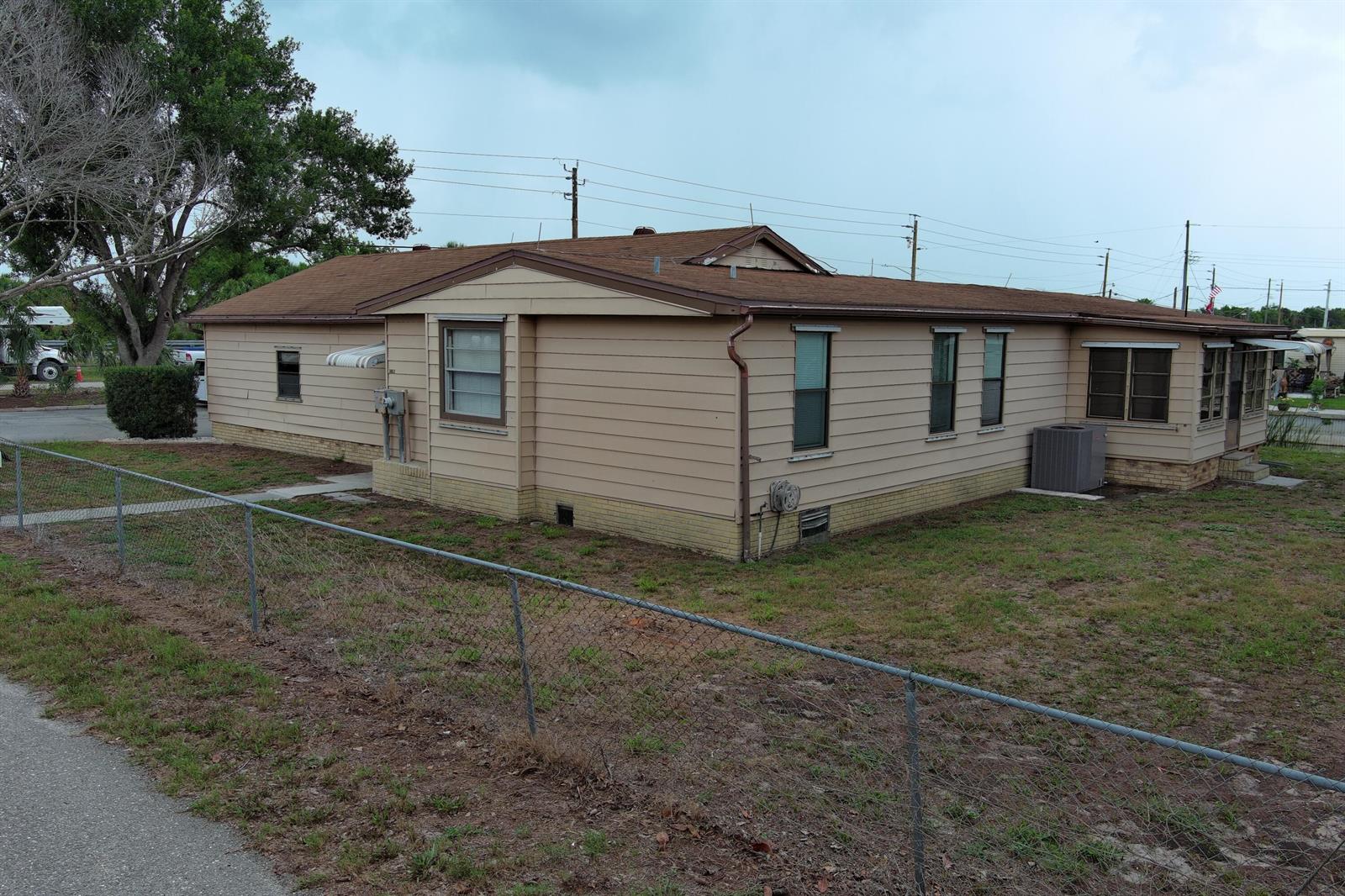 A tan, single-story manufactured home with a brown roof sits on a grassy lot — 1013 9th Street, Okeechobee FL 34974, OKEECHOBEE, FL