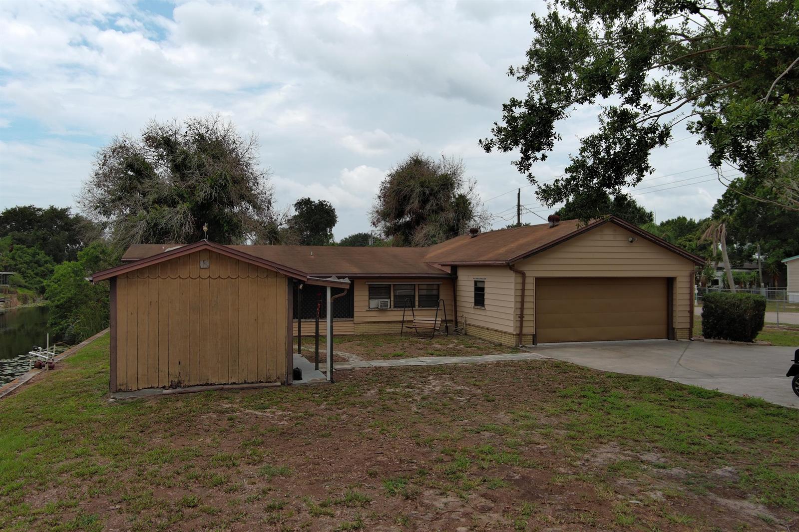 A single-story house with a brown garage, a side shed, and a grassy yard — 1013 9th Street, Okeechobee FL 34974, OKEECHOBEE, FL