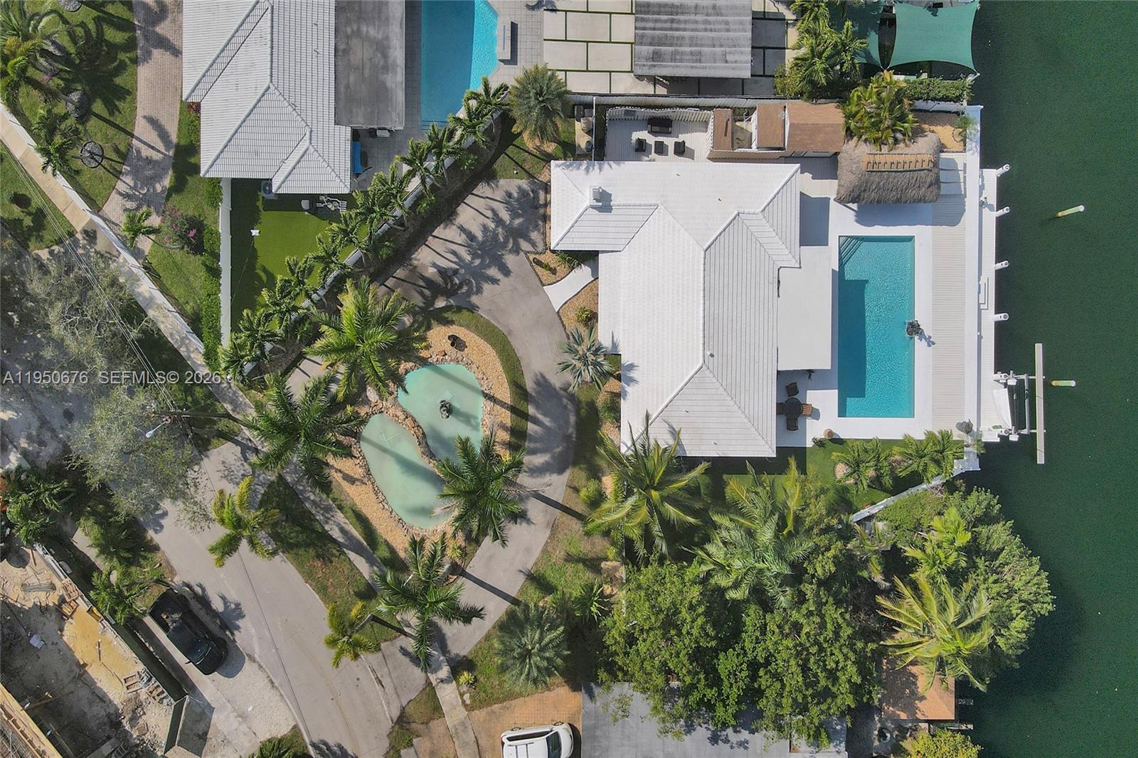 An aerial view shows a waterfront house with a pool, circular driveway, and palm trees — 1995 N Hibiscus Dr, North Miami FL 33181, NORTH MIAMI, FL
