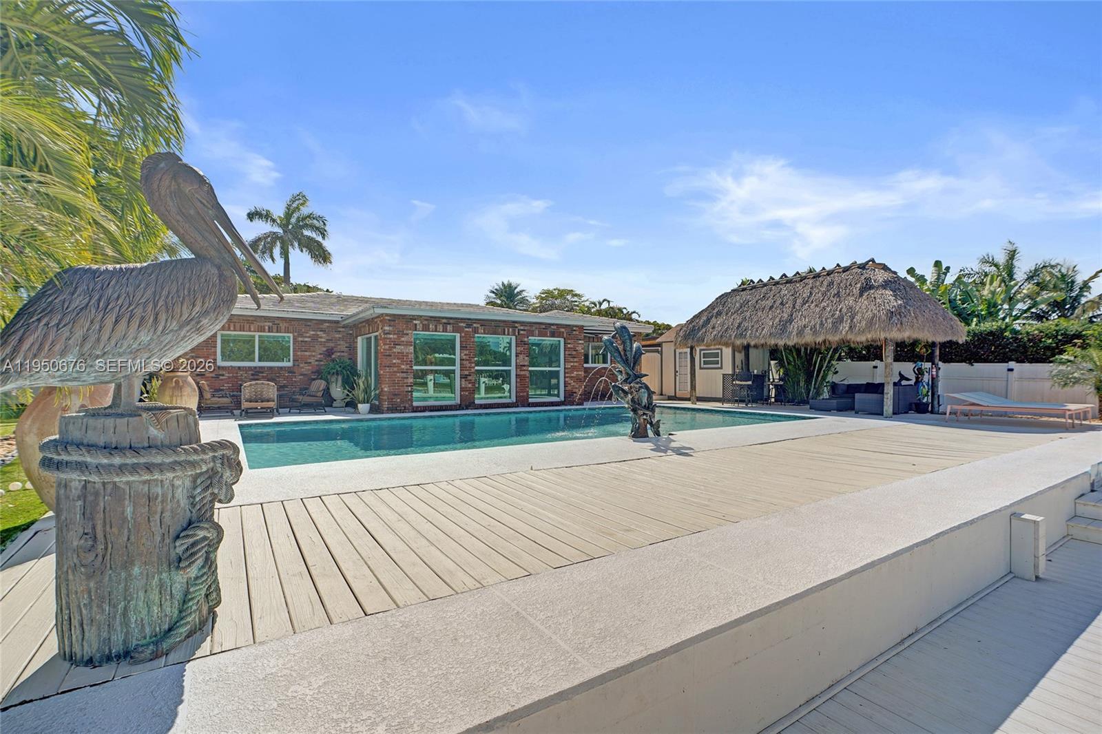 A backyard features a swimming pool with a fountain, a tiki hut, and a statue — 1995 N Hibiscus Dr, North Miami FL 33181, NORTH MIAMI, FL